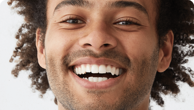 A smiling man with curly hair showcases his afro hairstyle, conveying a sense of warmth and approachability